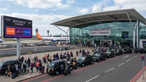Passengers loading luggage into a minicab at Gatwick Airport